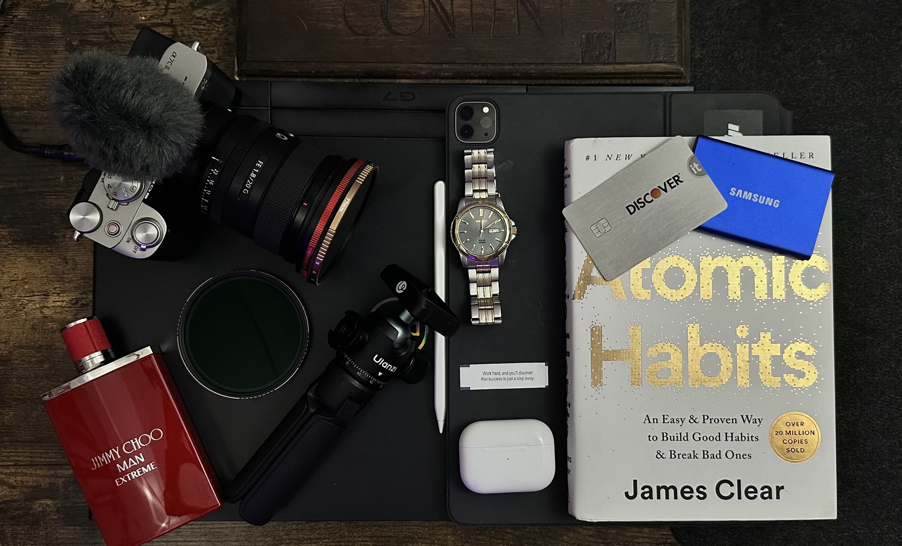 Everyday carry flat-lay — camera, watch and a copy of Atomic Habits.